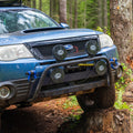 RalliTEK Subaru Forester flexed out on stump showing off front light bar and winch mount bumper system.