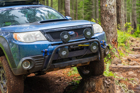 RalliTEK Subaru Forester flexed out on stump showing off front light bar and winch mount bumper system.