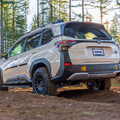 White 2026 Forester Wilderness driving on a dirt road with trees in the background