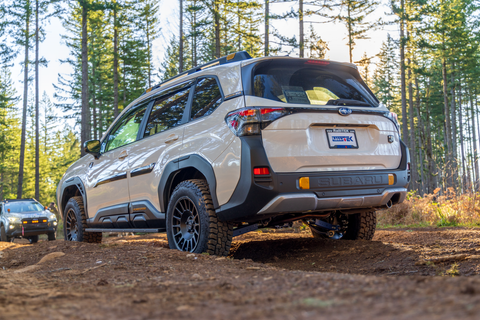 White 2026 Forester Wilderness driving on a dirt road with trees in the background